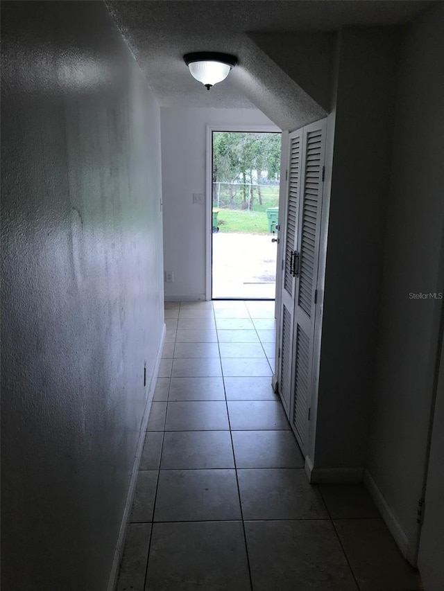 corridor featuring tile patterned floors and a textured ceiling