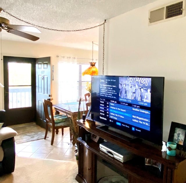 interior space with ceiling fan, a textured ceiling, and light tile patterned floors