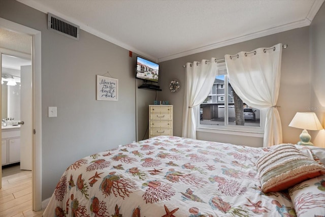 bedroom with crown molding, connected bathroom, a textured ceiling, and light hardwood / wood-style floors