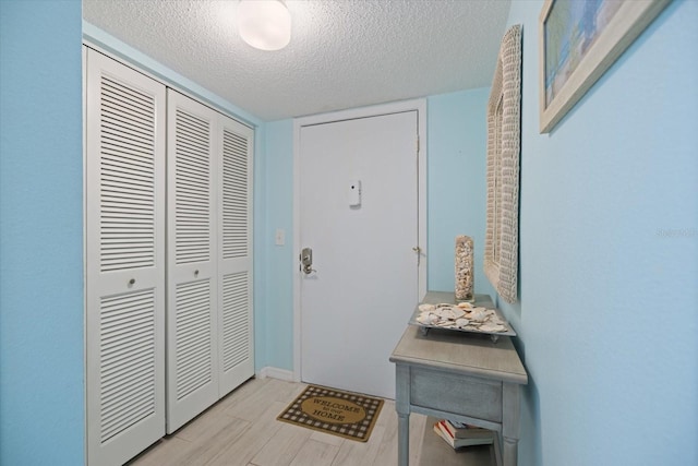 entryway featuring a textured ceiling and light hardwood / wood-style flooring