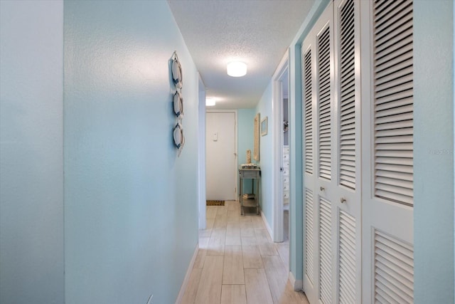 hall featuring a textured ceiling and light wood-type flooring