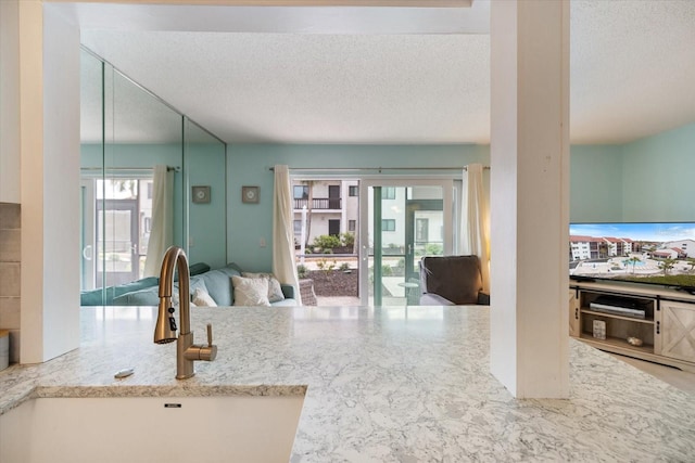 interior space featuring sink, light stone countertops, and a textured ceiling