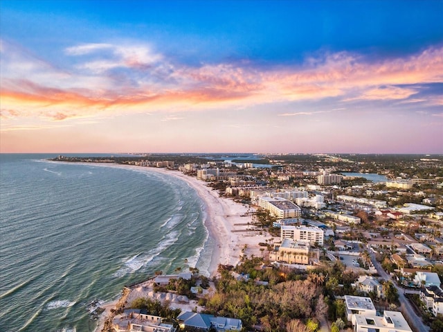 aerial view at dusk with a view of the beach and a water view