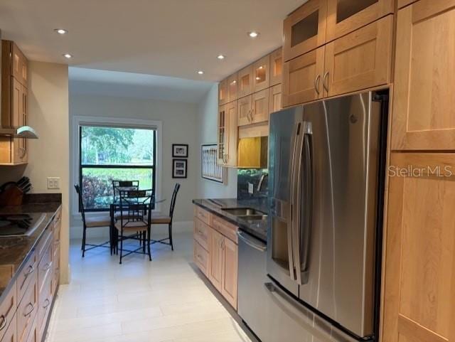 kitchen with appliances with stainless steel finishes, sink, light brown cabinets, and dark stone counters