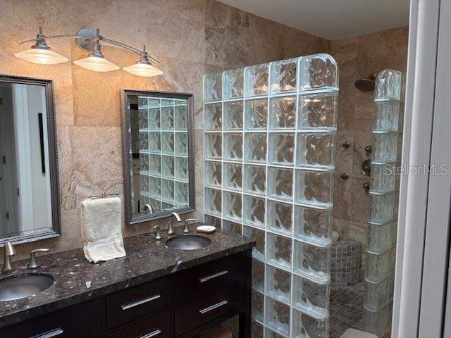 bathroom with tiled shower and vanity