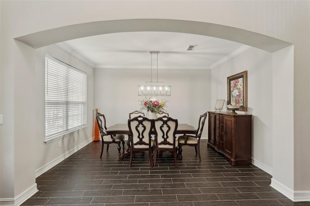 dining area with crown molding and a notable chandelier