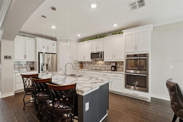 kitchen featuring a kitchen island with sink, sink, stainless steel appliances, and white cabinets