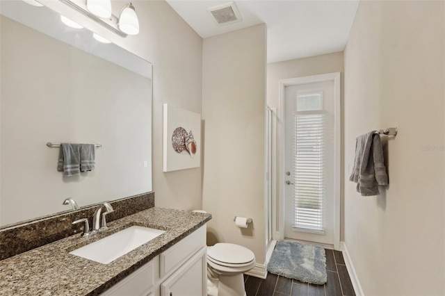 bathroom featuring vanity, an enclosed shower, and toilet