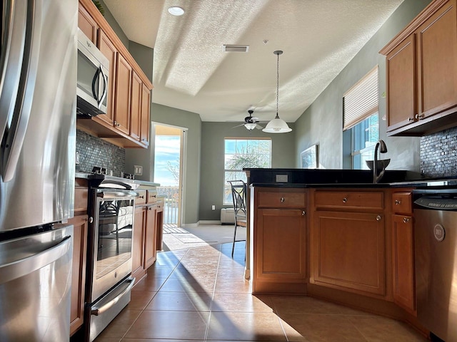 kitchen with dark tile patterned floors, backsplash, hanging light fixtures, and stainless steel appliances