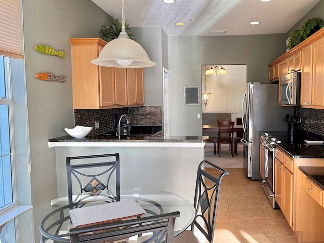 kitchen featuring stainless steel appliances, pendant lighting, light tile patterned floors, sink, and kitchen peninsula