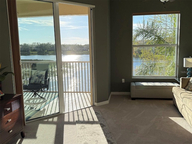 doorway to outside featuring a water view, carpet flooring, and a healthy amount of sunlight