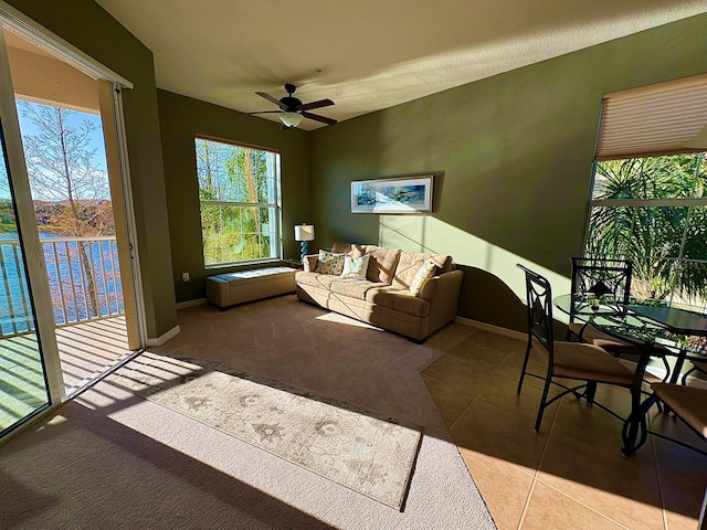 tiled living room with a water view and ceiling fan