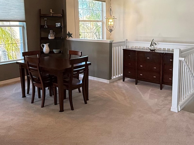 dining area with light carpet and a notable chandelier