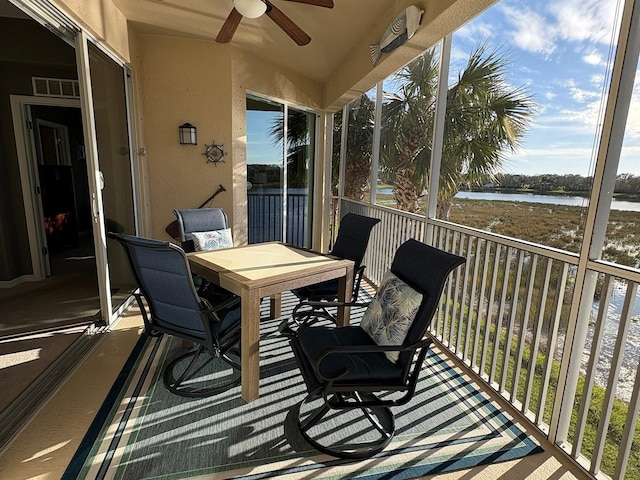 sunroom with a water view and ceiling fan