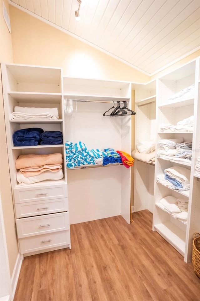 walk in closet with light hardwood / wood-style flooring and vaulted ceiling