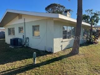 view of side of home with cooling unit and a lawn