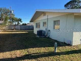 view of home's exterior with cooling unit and a lawn