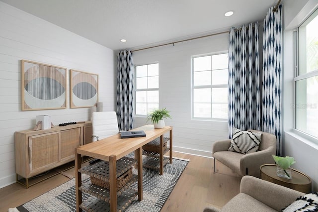 home office with plenty of natural light, light wood-type flooring, and wood walls