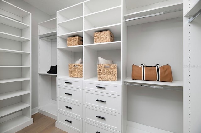 walk in closet with light hardwood / wood-style floors