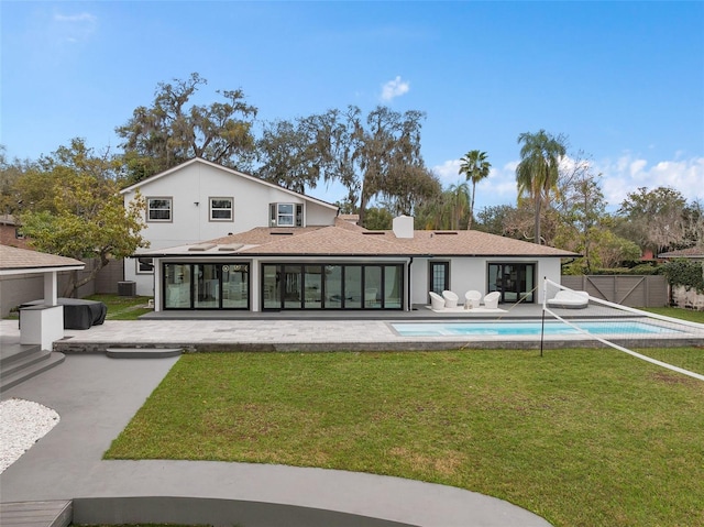 rear view of property with a lawn, a fenced in pool, a patio, fence, and stucco siding