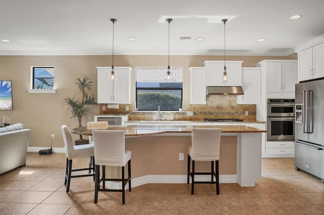 kitchen featuring a kitchen bar, a center island, pendant lighting, stainless steel appliances, and white cabinets