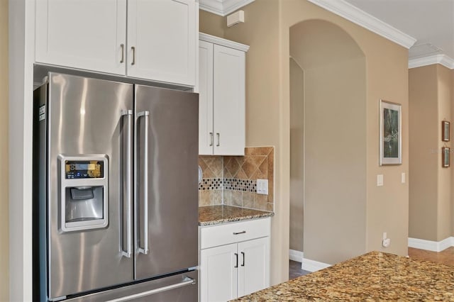 kitchen featuring tasteful backsplash, white cabinetry, light stone counters, crown molding, and stainless steel fridge