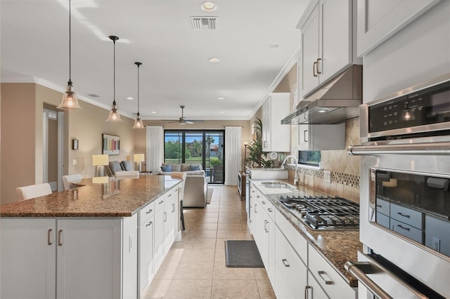 kitchen with appliances with stainless steel finishes, a center island, white cabinets, a kitchen bar, and dark stone counters