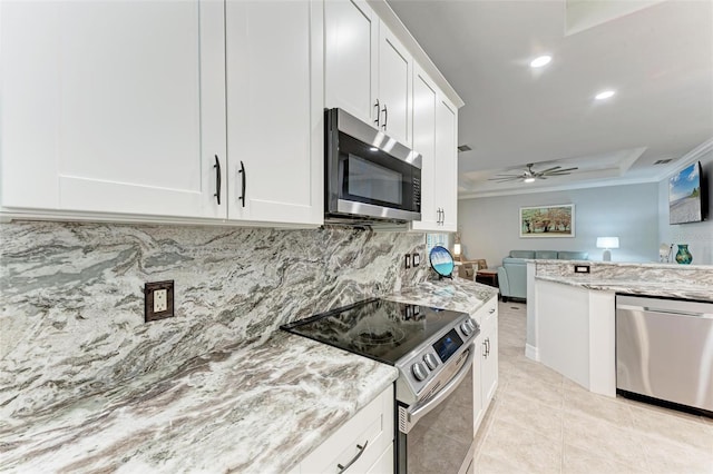 kitchen with light tile patterned flooring, white cabinetry, light stone counters, appliances with stainless steel finishes, and ceiling fan