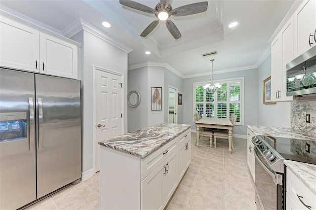 kitchen with stainless steel appliances, a raised ceiling, white cabinets, and crown molding