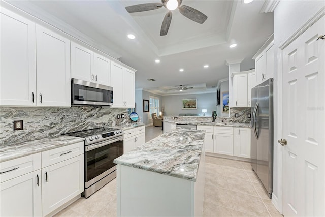 kitchen featuring a raised ceiling, white cabinets, decorative backsplash, kitchen peninsula, and stainless steel appliances