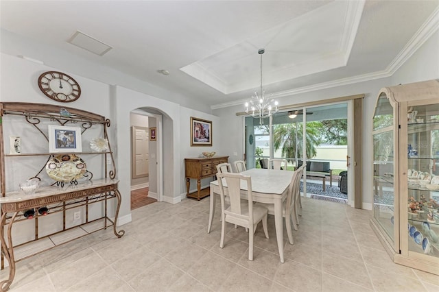 dining area with an inviting chandelier, a tray ceiling, light tile patterned flooring, and crown molding