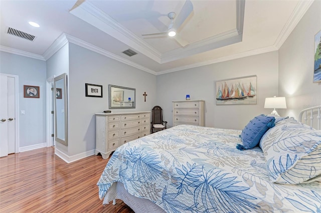 bedroom featuring a raised ceiling, crown molding, wood-type flooring, and ceiling fan