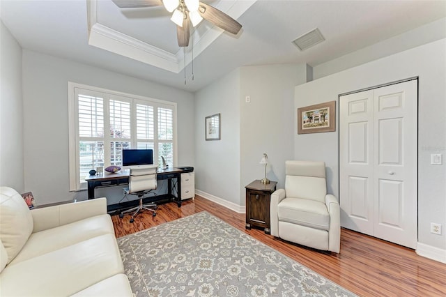 office with crown molding, hardwood / wood-style floors, a tray ceiling, and ceiling fan