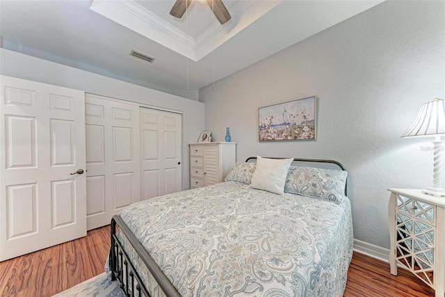 bedroom with crown molding, ceiling fan, wood-type flooring, and a closet