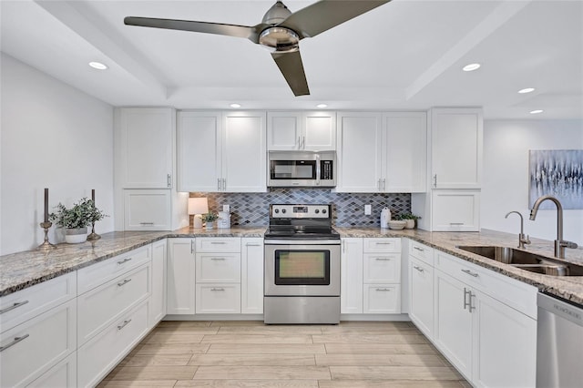 kitchen featuring tasteful backsplash, white cabinetry, appliances with stainless steel finishes, and sink