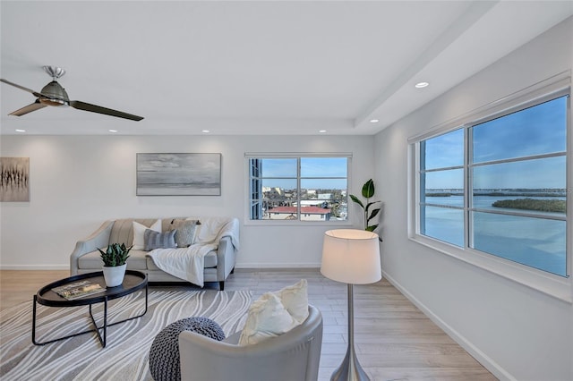 living room with light wood-type flooring, ceiling fan, and a water view