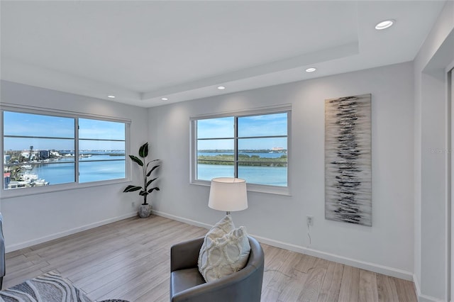 sitting room with light hardwood / wood-style flooring, plenty of natural light, and a water view