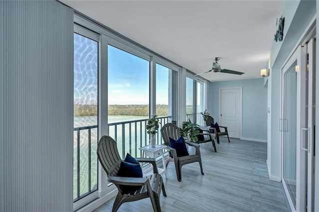 sunroom featuring ceiling fan and a water view