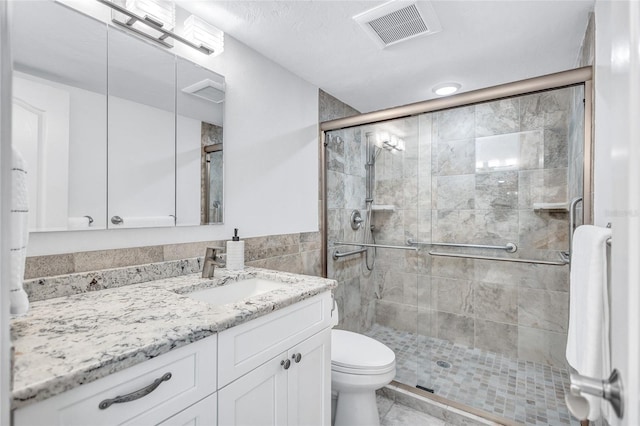 bathroom featuring a shower with door, vanity, tile walls, and toilet