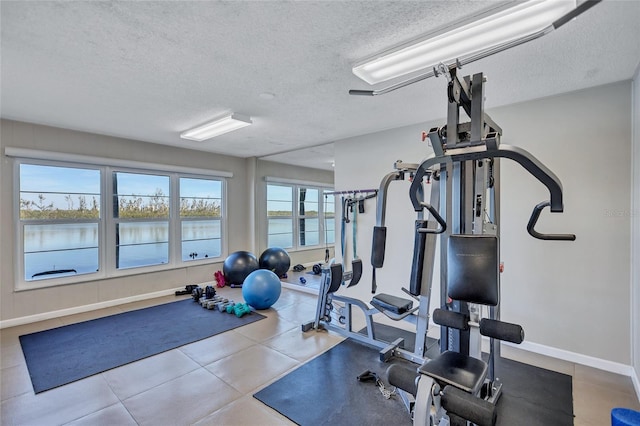 workout area with a water view and a textured ceiling