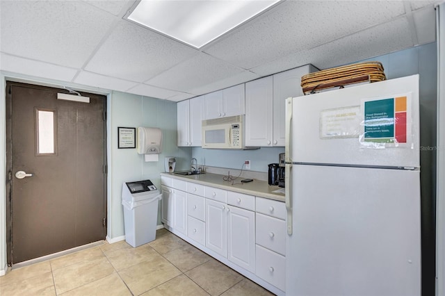 kitchen featuring light tile patterned flooring, sink, white cabinetry, a paneled ceiling, and white appliances