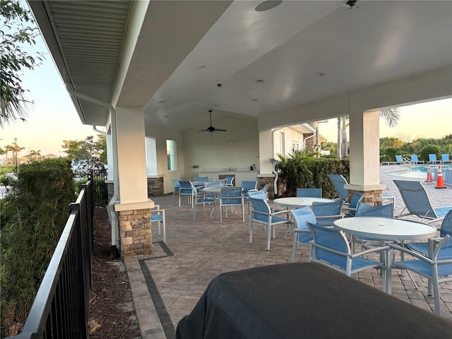 patio terrace at dusk featuring a community pool and ceiling fan