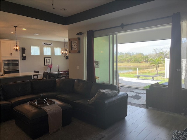 living room with a notable chandelier, hardwood / wood-style flooring, and a water view