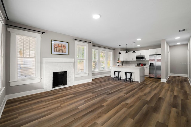 unfurnished living room featuring dark hardwood / wood-style floors and a brick fireplace