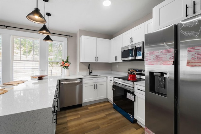 kitchen featuring appliances with stainless steel finishes, decorative light fixtures, sink, white cabinets, and dark wood-type flooring