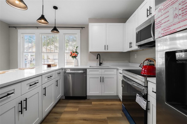 kitchen featuring appliances with stainless steel finishes, dark hardwood / wood-style floors, pendant lighting, sink, and white cabinets