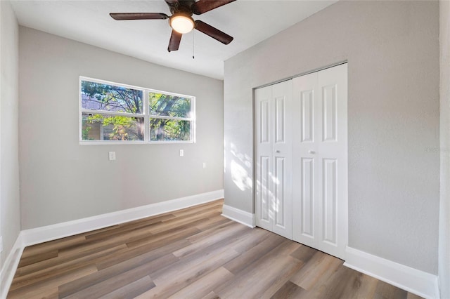 unfurnished bedroom with hardwood / wood-style floors, ceiling fan, and a closet