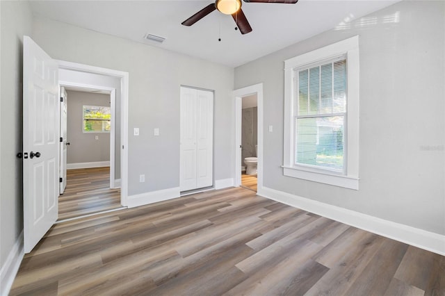 unfurnished bedroom with hardwood / wood-style floors, ensuite bath, a closet, and ceiling fan