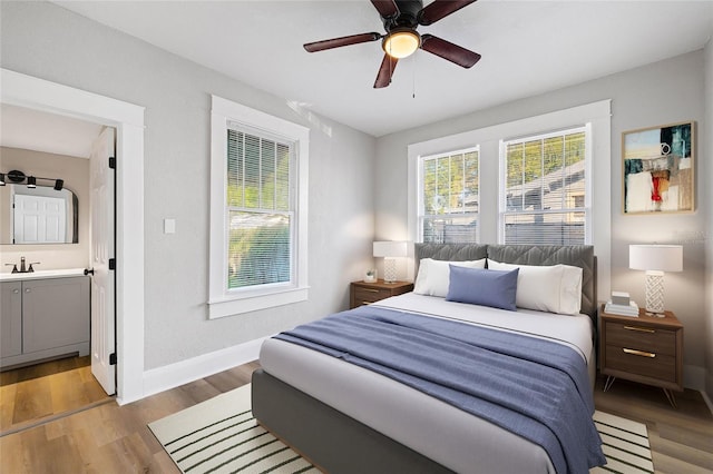 bedroom with ensuite bathroom, light wood-type flooring, sink, and ceiling fan