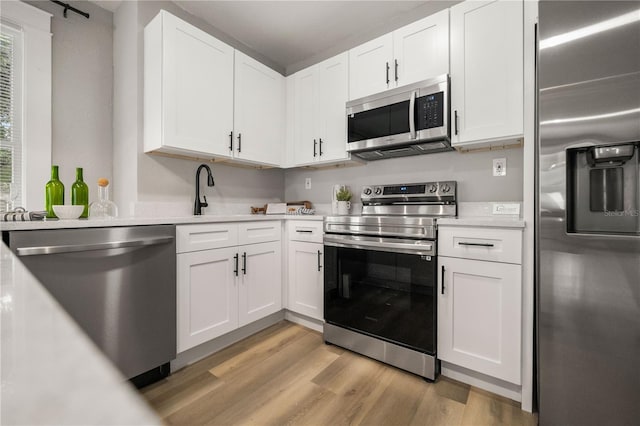1010 E Lake Ave, Tampa, FL 33605 - kitchen featuring stainless steel appliances, light wood-style floors, light countertops, and white cabinets